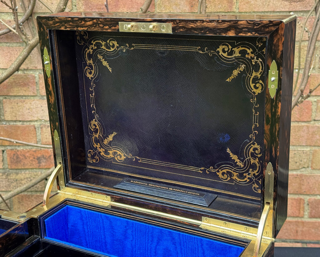 View of interior gold tooled leather on the lid underside of an Antique Jewellery Box in Coromandel with Betjemann Patent Automatic Mechanism.