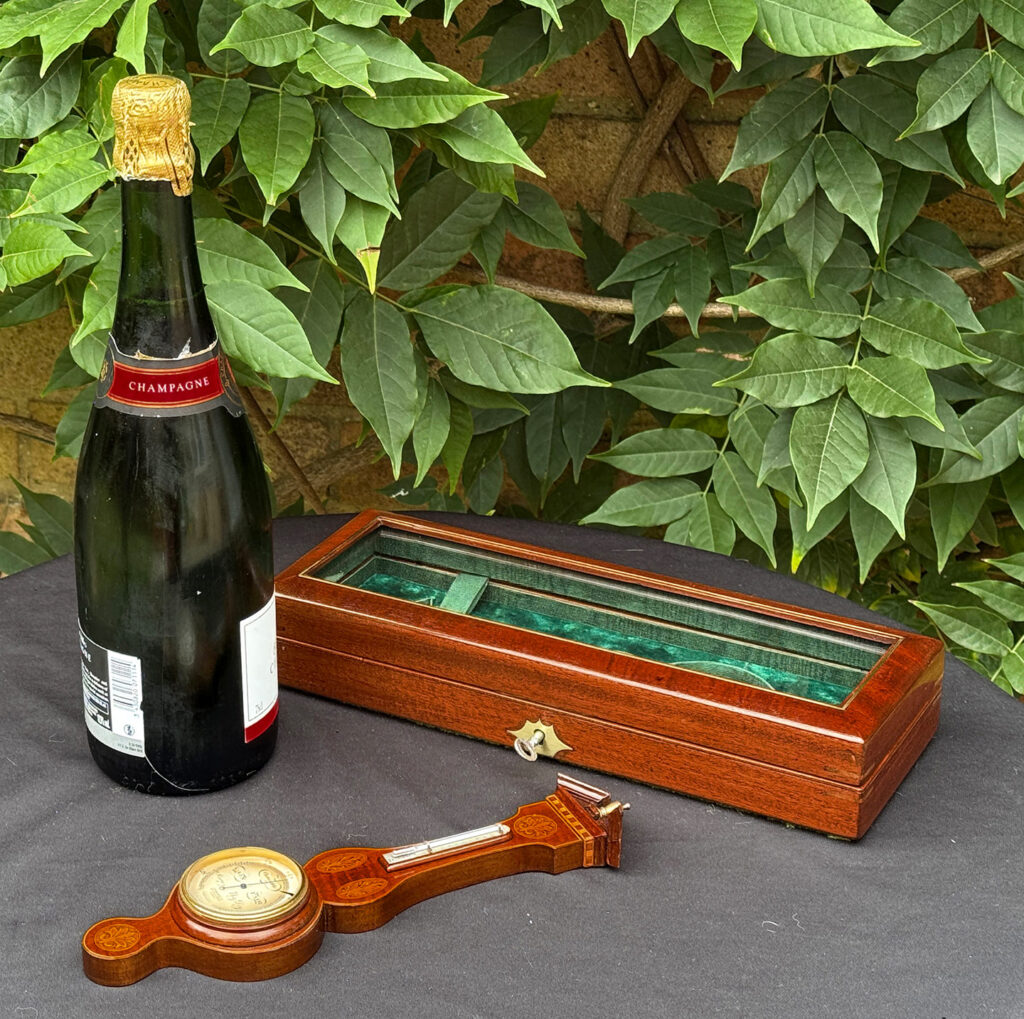 Size comparison of the barometer and its display case against a 75cl wine bottle.