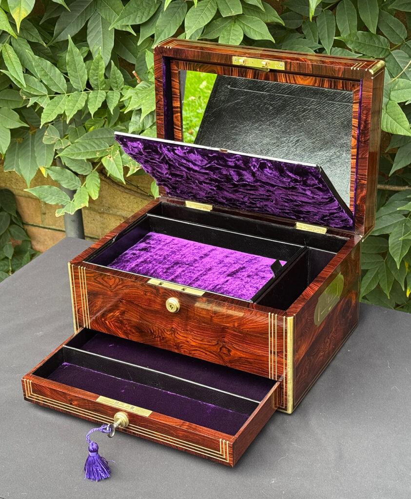 Front right internal view of an antique jewellery box in kingwood, by Halstaff & Hannaford with lid flap opened to reveal a mirror.