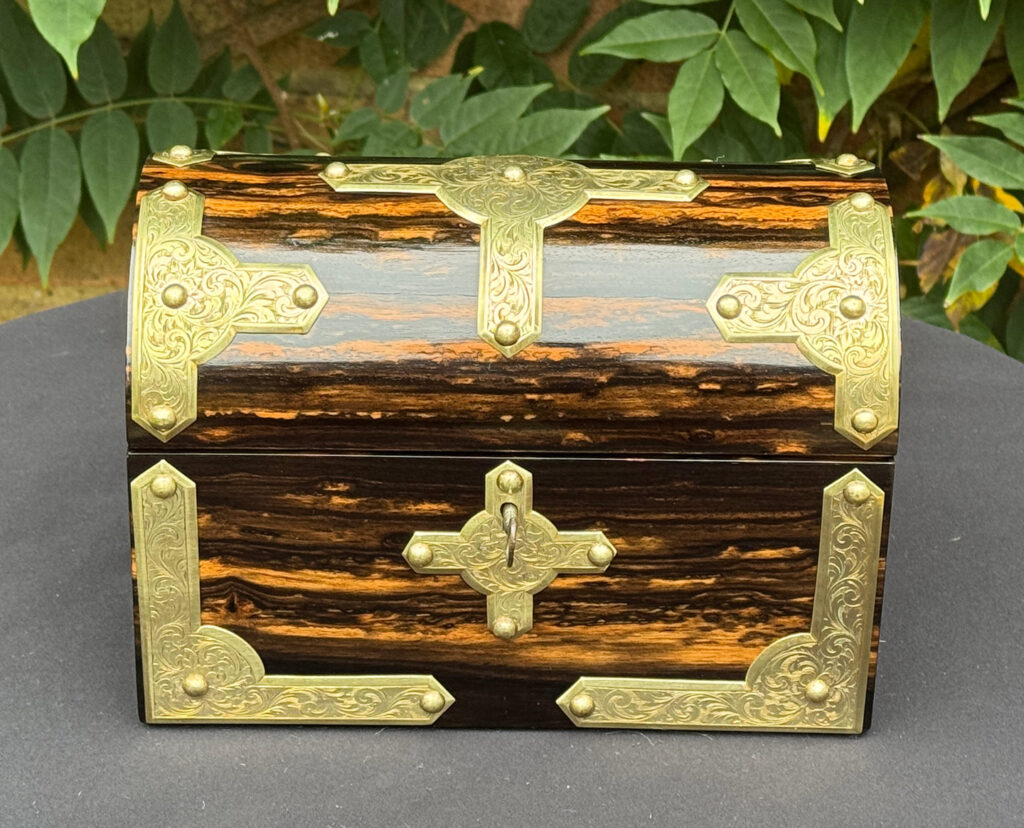 Front view of an antique jewellery box in coromandel with engraved brass overlay.