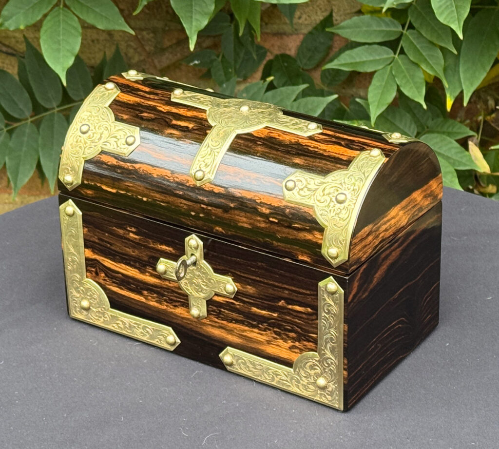 Front right view of an antique jewellery box in coromandel with engraved brass overlay.