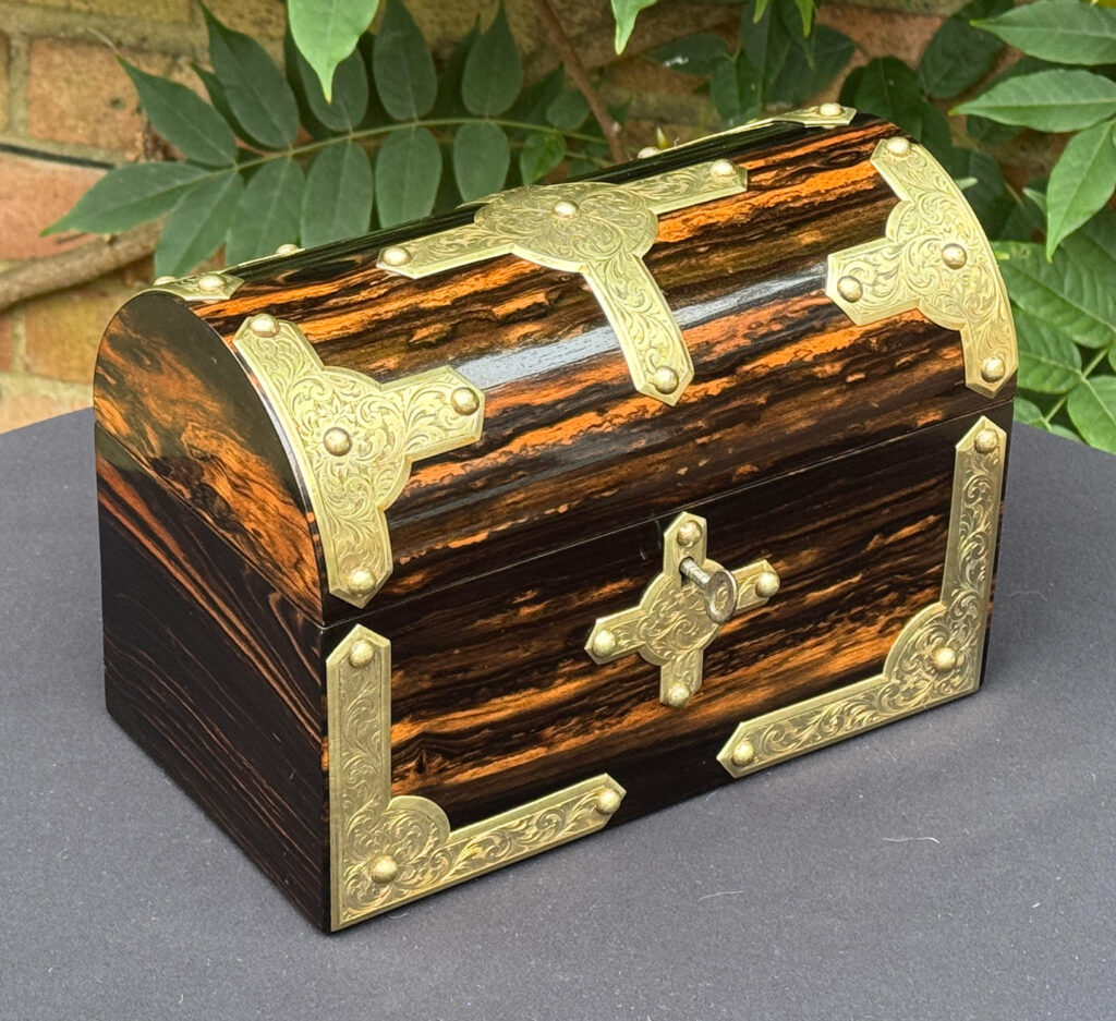 Front left view of an antique jewellery box in coromandel with engraved brass overlay.