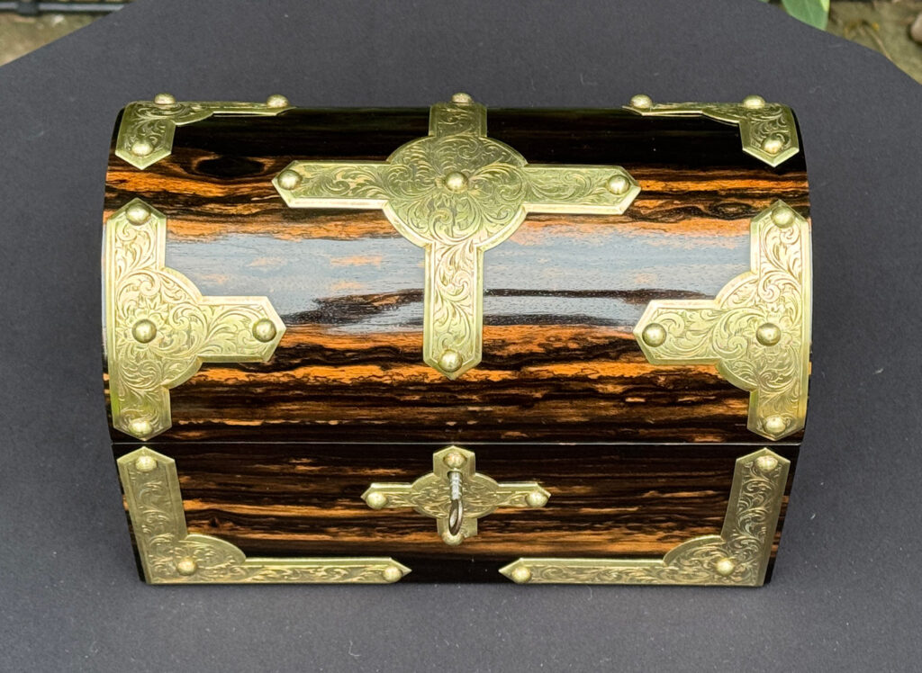 Overhead view of an antique jewellery box in coromandel with engraved brass overlay.