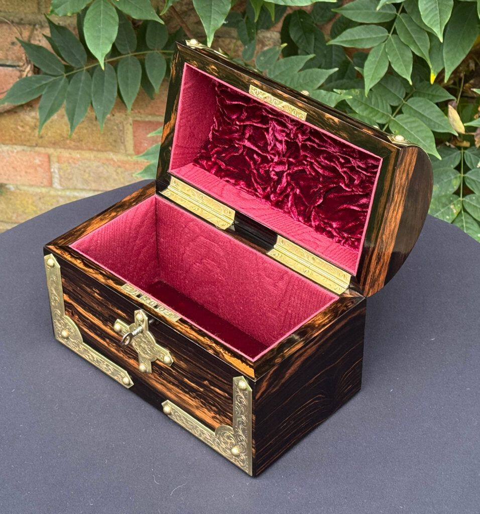 Front right internal view of an antique jewellery box in coromandel with engraved brass overlay.