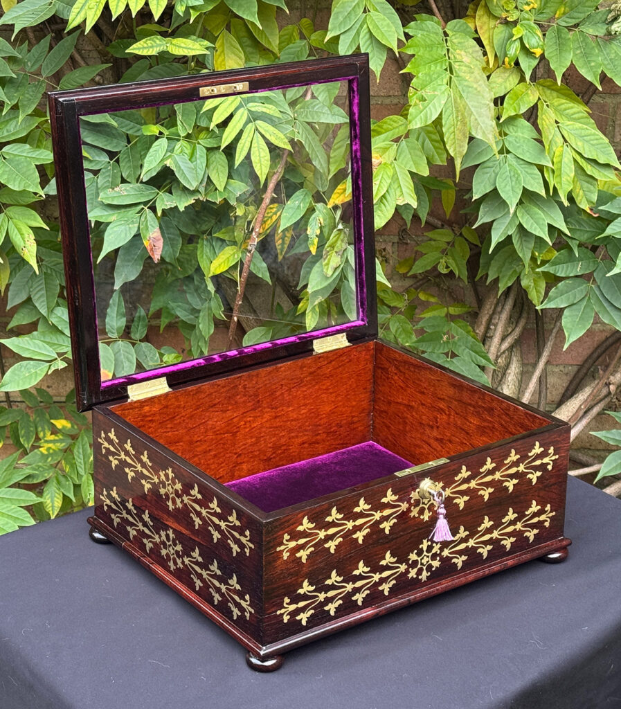 Front left internal view of an antique rosewood brass inlaid glass display jewellery box.