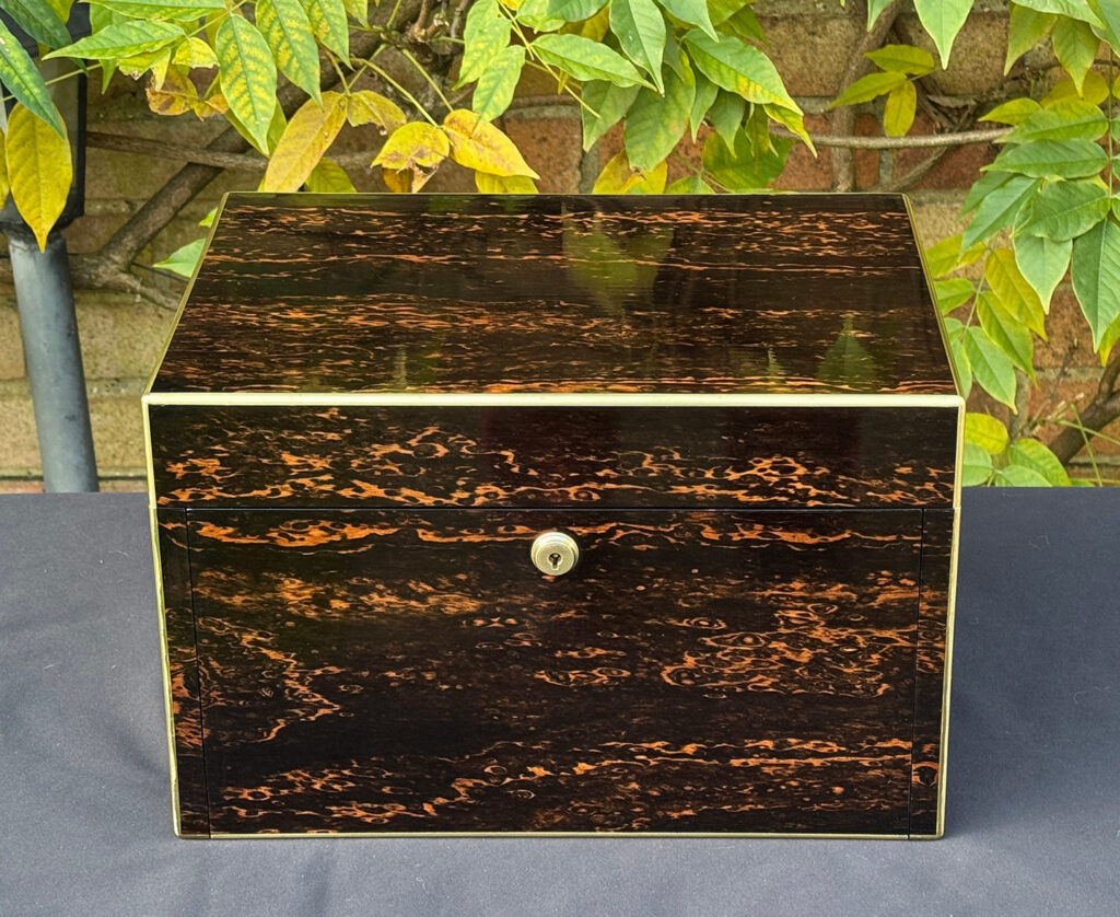 Front view of an antique jewellery box in coromandel with two concealed drawers.