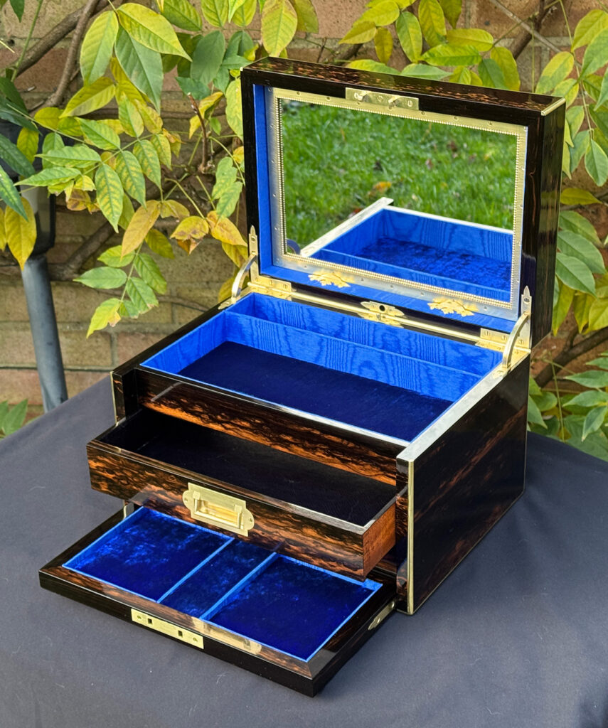 Front right internal view of an antique jewellery box in coromandel with two concealed drawers, with top drawer opened.