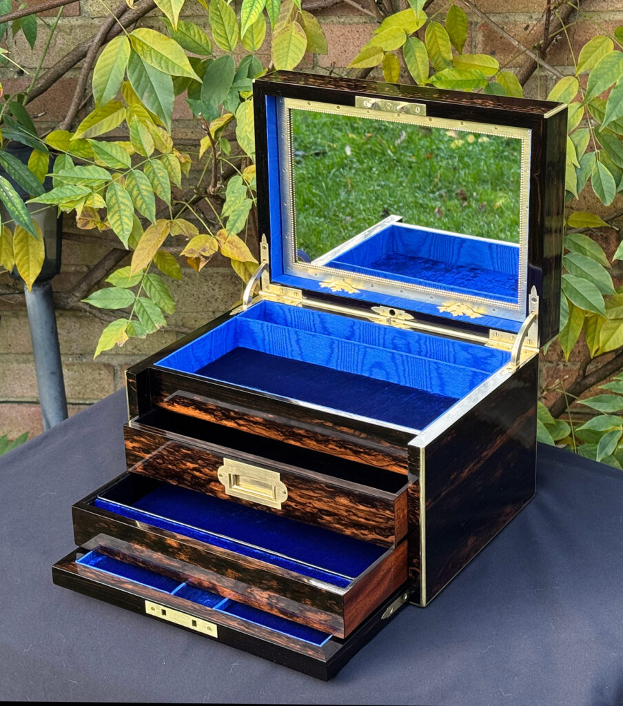 Front right internal view of an antique jewellery box in coromandel with two concealed drawers, with lower drawer opened.
