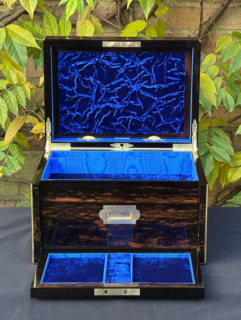 Front internal view of an antique jewellery box in coromandel with two concealed drawers, with ruched velvet panel on display.
