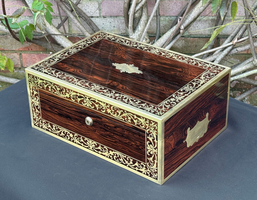Front right view of an antique jewellery box in Rosewood with scrollwork brass inlay, by Edwards.