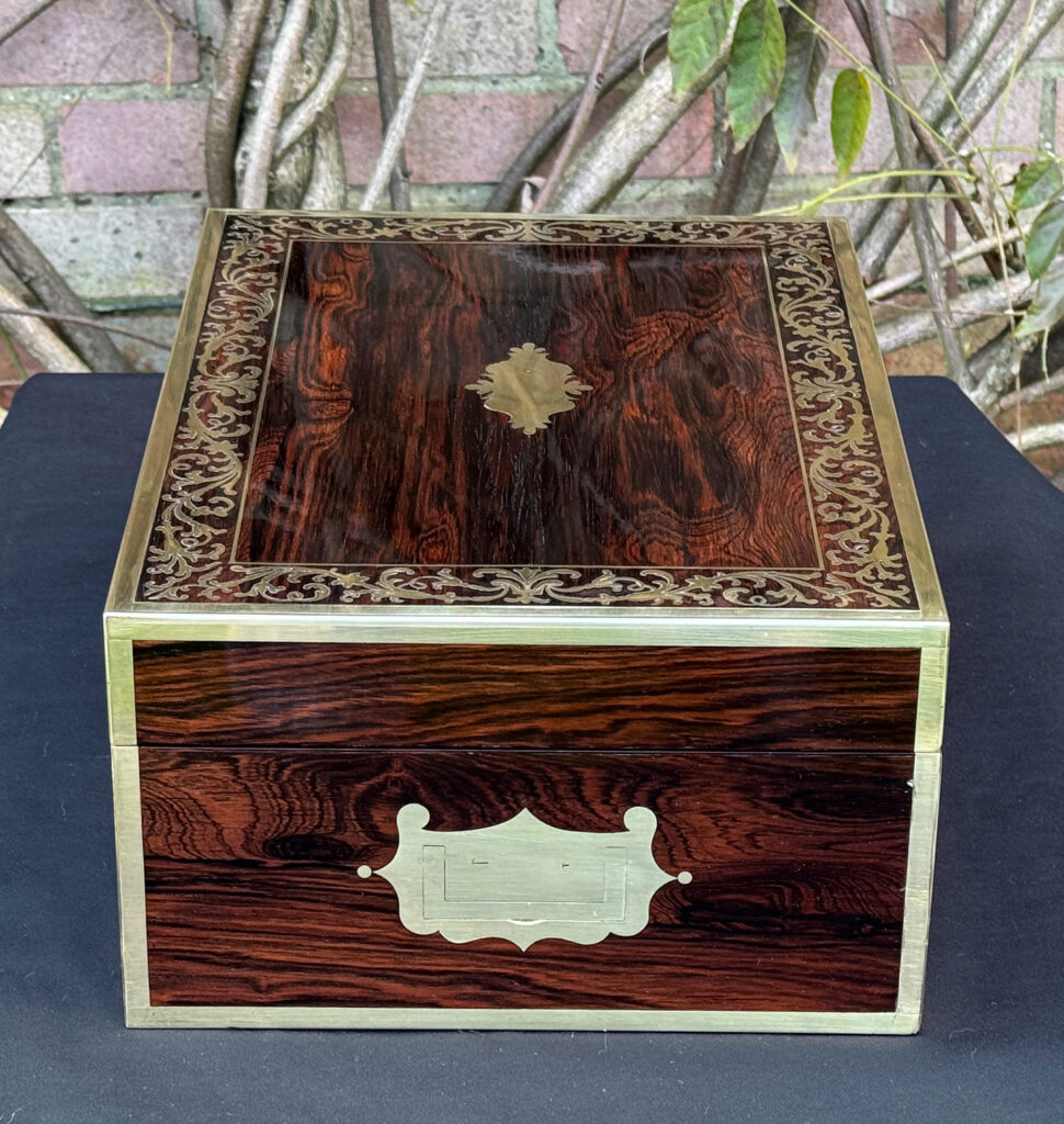Right side view of an antique jewellery box in Rosewood with scrollwork brass inlay, by Edwards.
