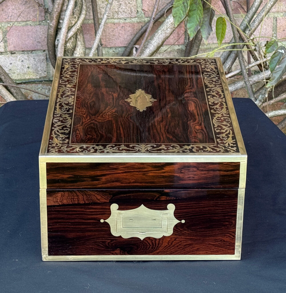 Left side view of an antique jewellery box in Rosewood with scrollwork brass inlay, by Edwards.