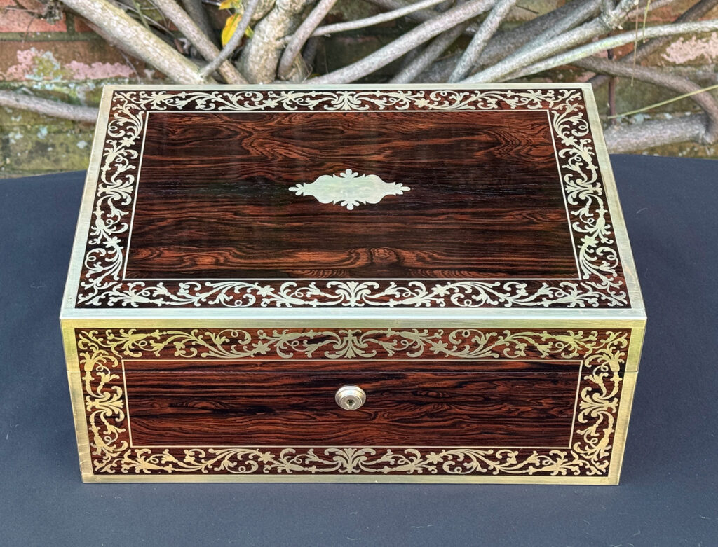 Overhead view of an antique jewellery box in Rosewood with scrollwork brass inlay, by Edwards.