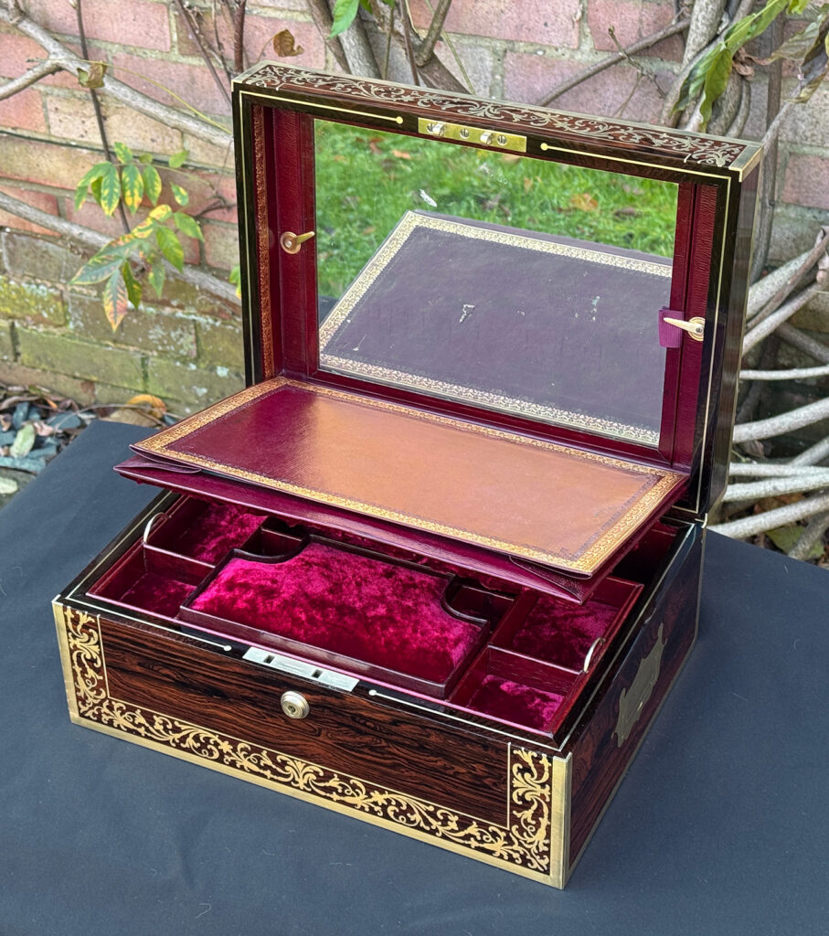 Front right internal view of an antique jewellery box in Rosewood with scrollwork brass inlay, by Edwards, with mirror stowed in the lid.