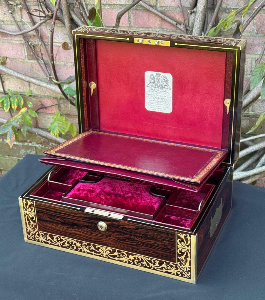 Front right internal view of an antique jewellery box in Rosewood with scrollwork brass inlay, by Edwards, with the paper manufacturer's label on display.