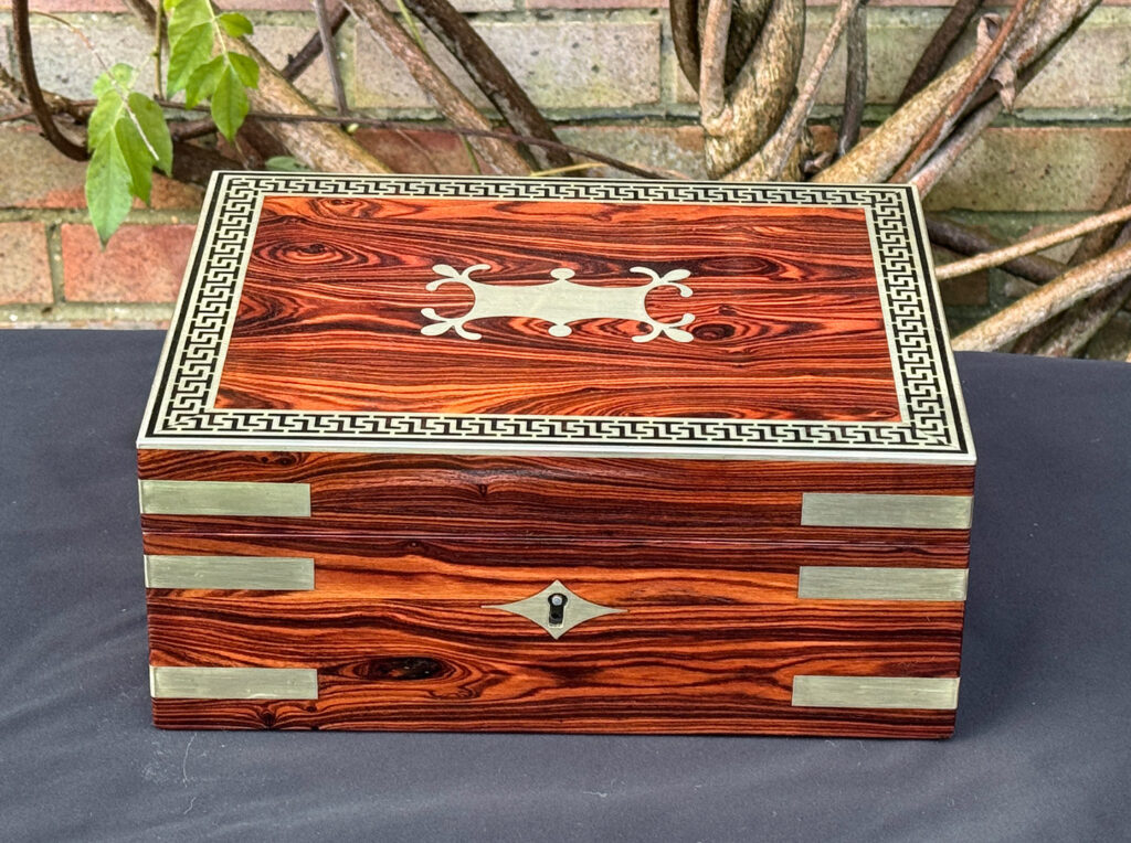 Front view of an antique jewellery box in kingwood with brass inlay.