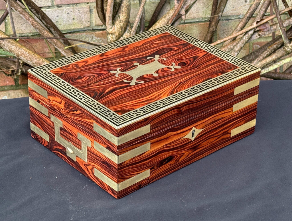 Front left view of an antique jewellery box in kingwood with brass inlay.