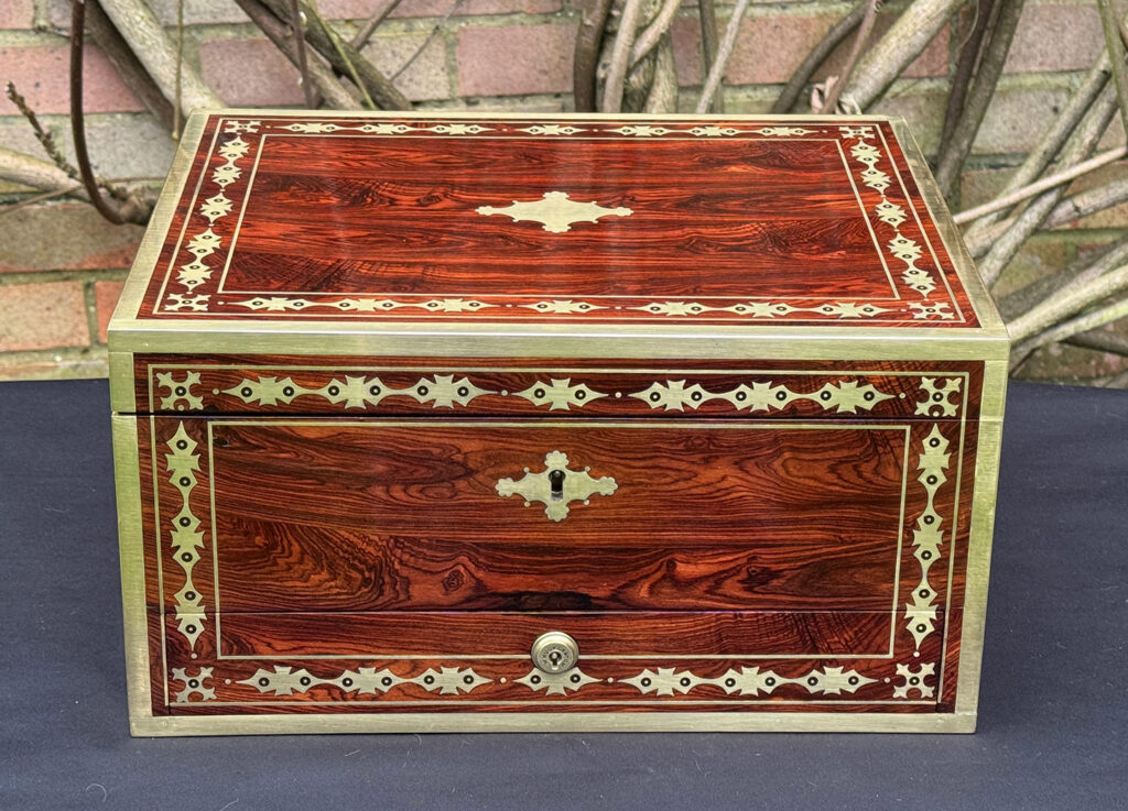 Front view of an antique jewellery box in kingwood with decorative brass inlay.