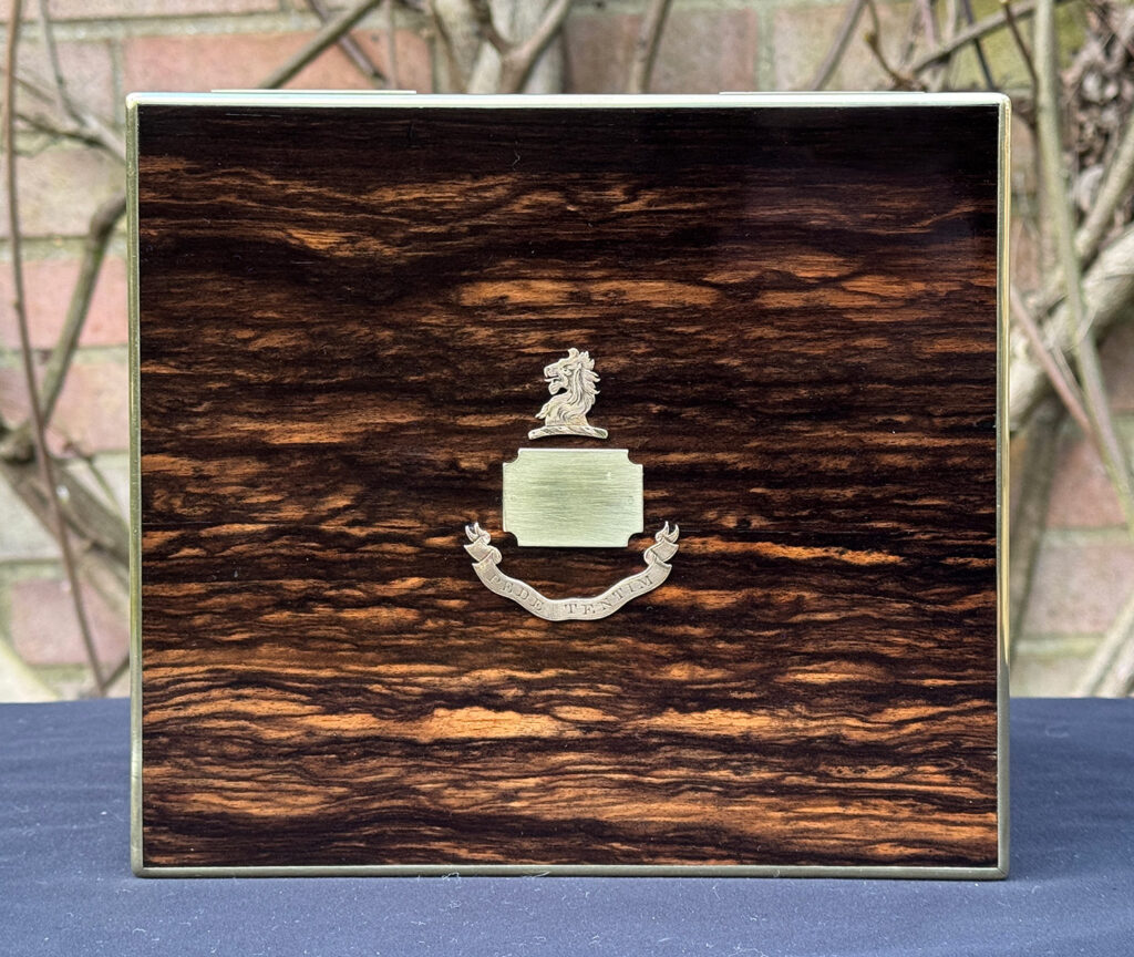 Close up view of the family crest from a miniature antique jewellery box in coromandel, by George Betjemann & Sons.