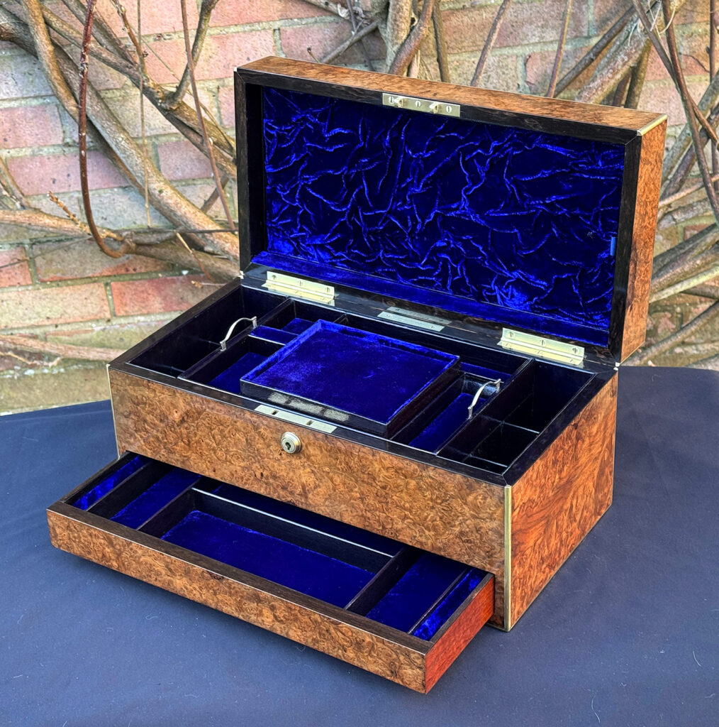 Front right internal view of a large antique jewellery box in burr walnut, with lower drawer opened.