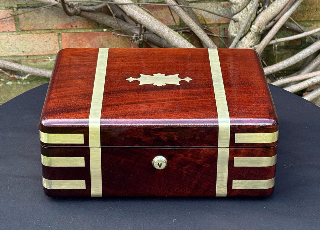 Front view of an antique radial edged travelling jewellery box in mahogany.