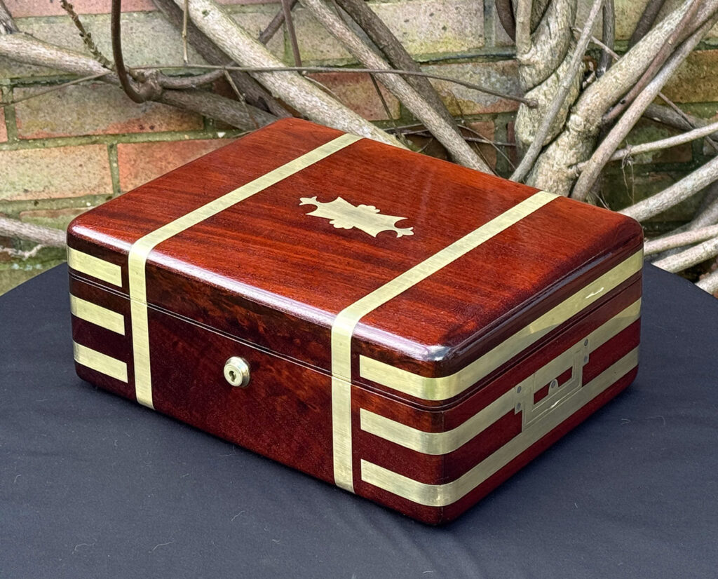 Front right view of an antique radial edged travelling jewellery box in mahogany.