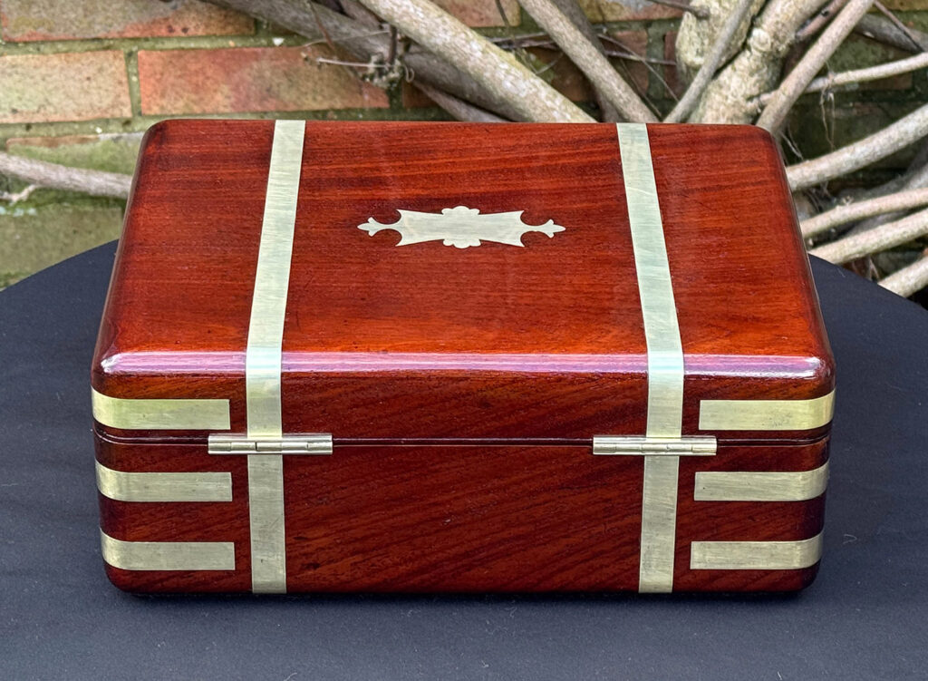 Rear view of an antique radial edged travelling jewellery box in mahogany.