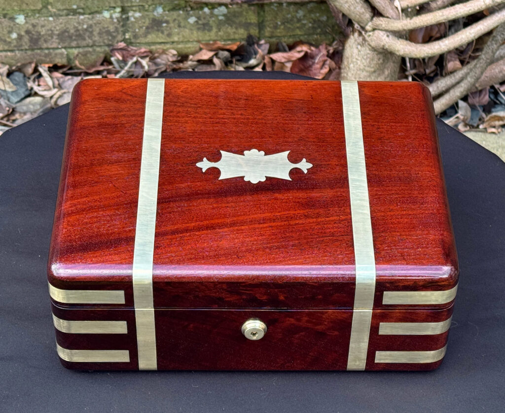 Overhead view of an antique radial edged travelling jewellery box in mahogany.Front right