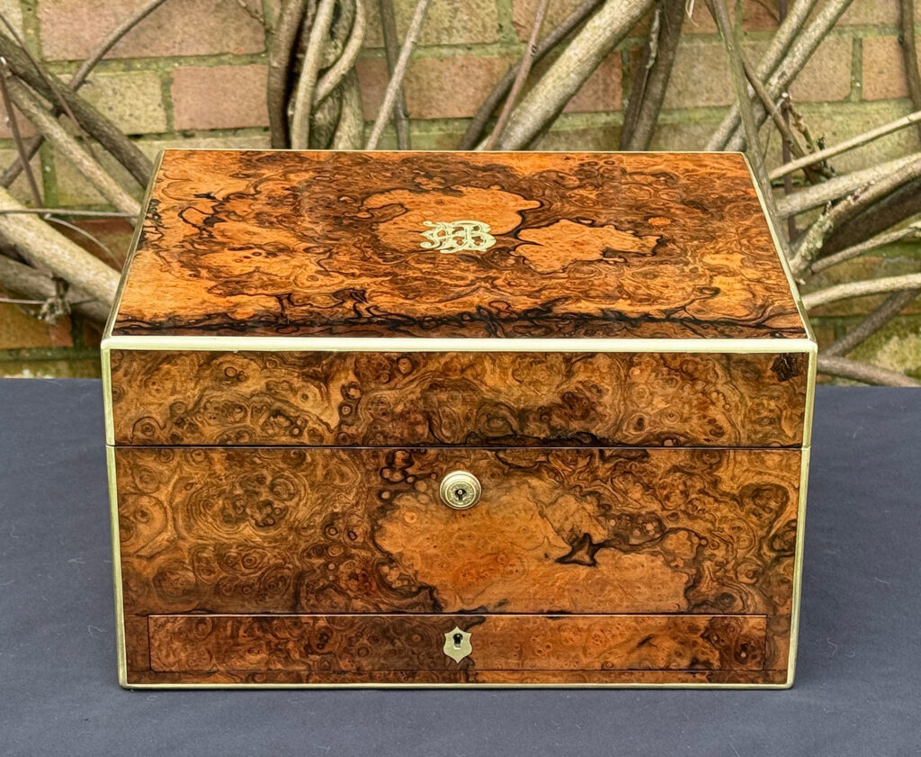 Front view of an antique jewellery box in burr walnut by Halstaff & Hannaford.