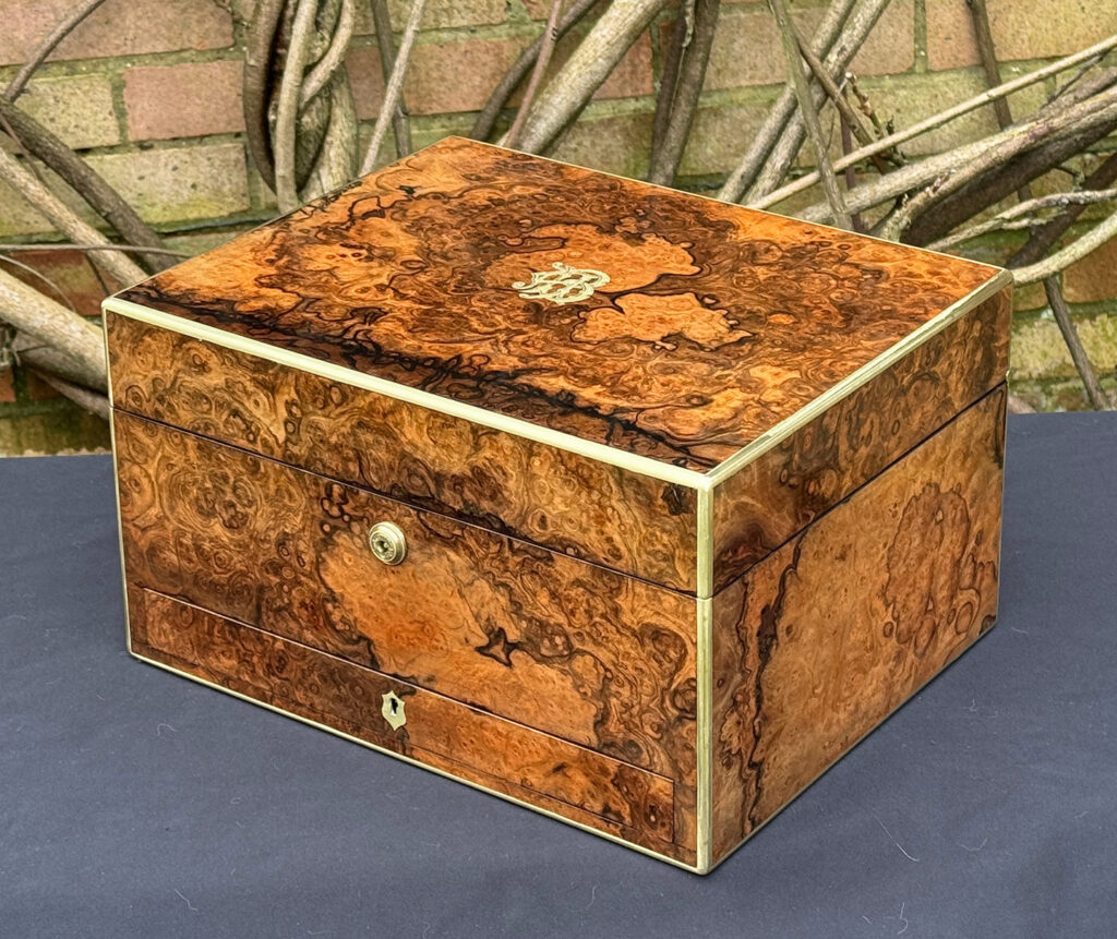 Front right view of an antique jewellery box in burr walnut by Halstaff & Hannaford.