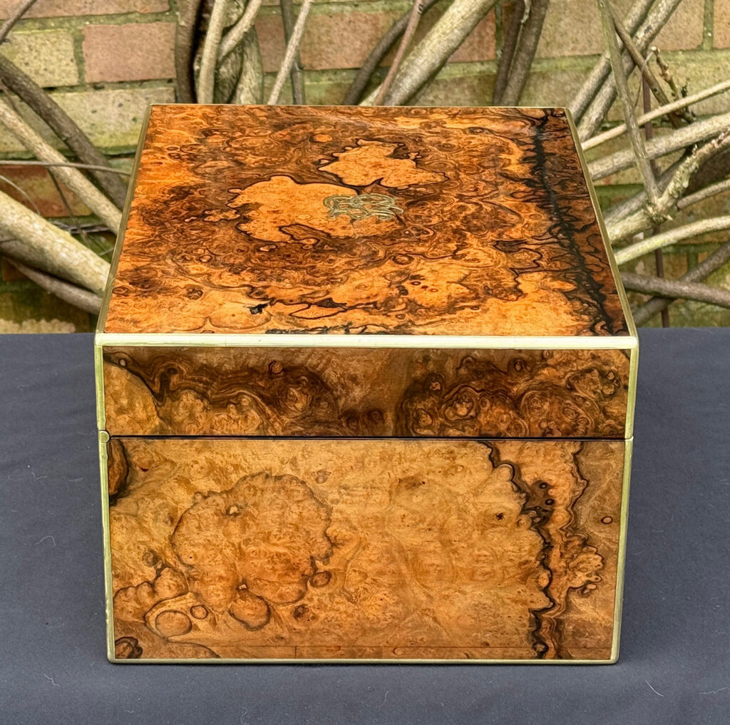 Left side view of an antique jewellery box in burr walnut by Halstaff & Hannaford.