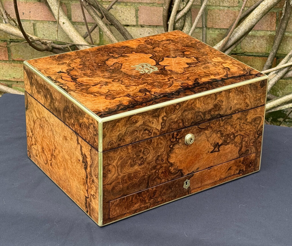 Front left view of an antique jewellery box in burr walnut by Halstaff & Hannaford.