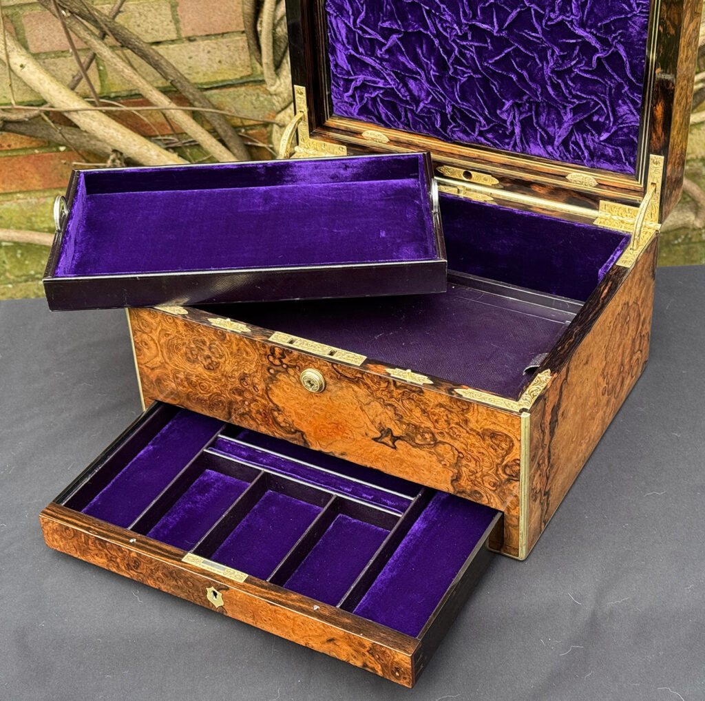 Overhead interior view of an antique jewellery box in burr walnut by Halstaff & Hannaford, with the top tray removed.