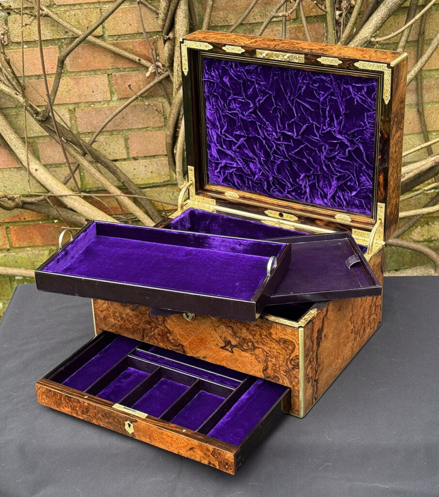 Front right interior view of an antique jewellery box in burr walnut by Halstaff & Hannaford, with both trays removed.