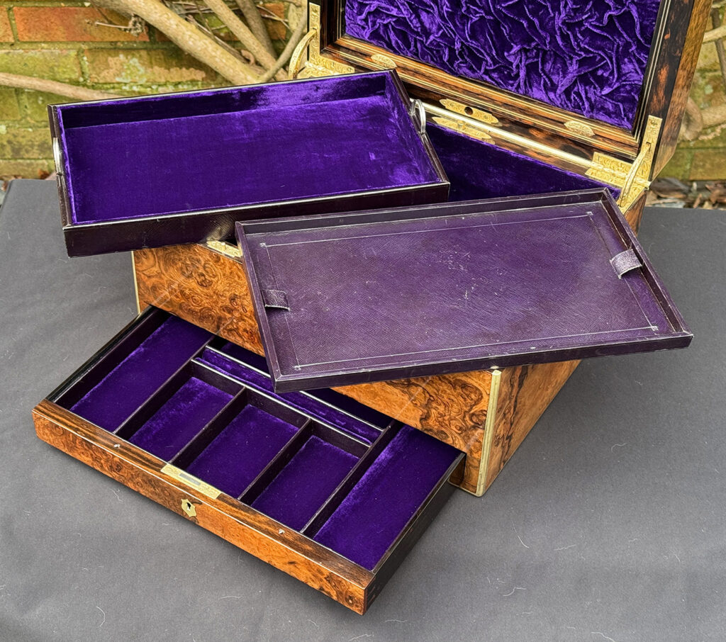 Closer interior view of an antique jewellery box in burr walnut by Halstaff & Hannaford, with both trays removed.