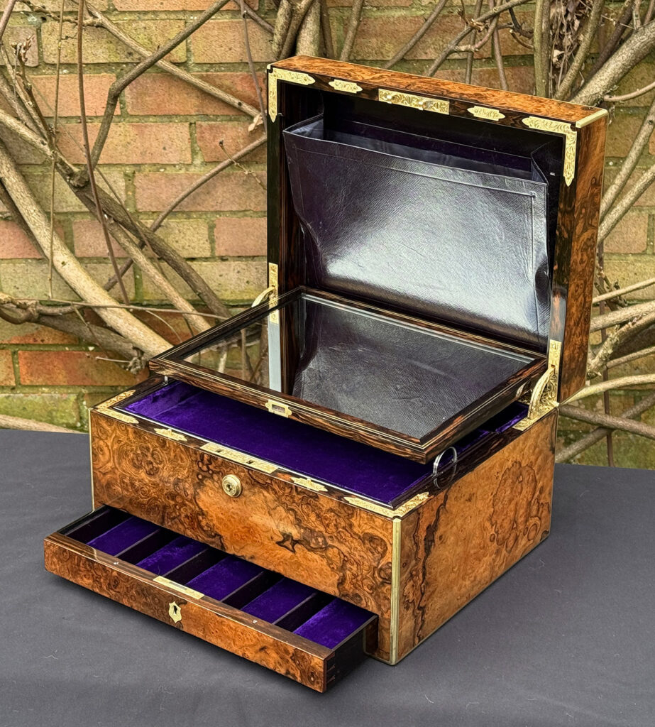 Front right interior view of an antique jewellery box in burr walnut by Halstaff & Hannaford, with mirror panel dropped forward.