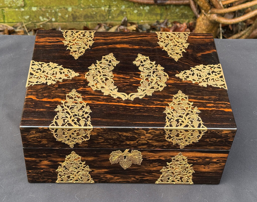 Overhead view of an antique sewing box in coromandel with fretwork foliate brass overlay.