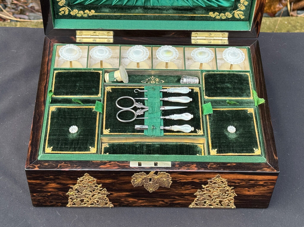 Overhead interior view of an antique sewing box in coromandel with fretwork foliate brass overlay.