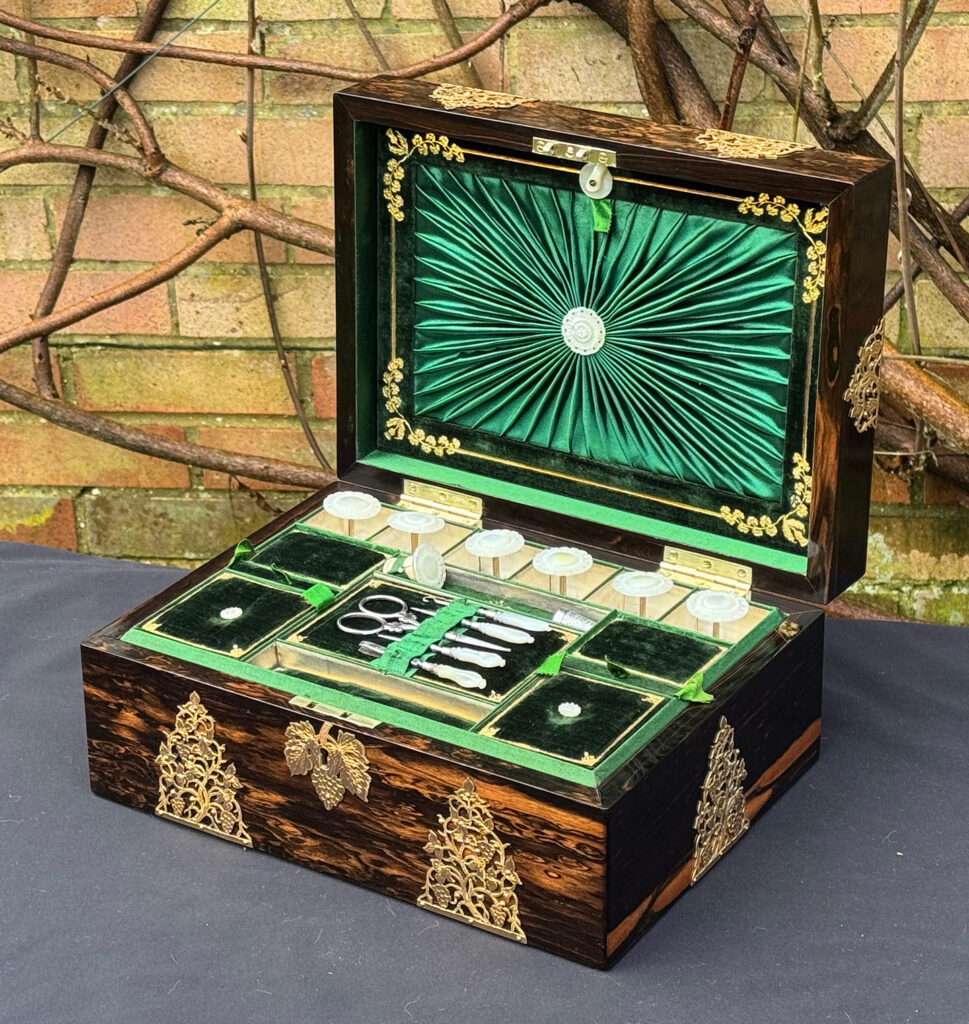 Front right interior view of an antique sewing box in coromandel with fretwork foliate brass overlay.