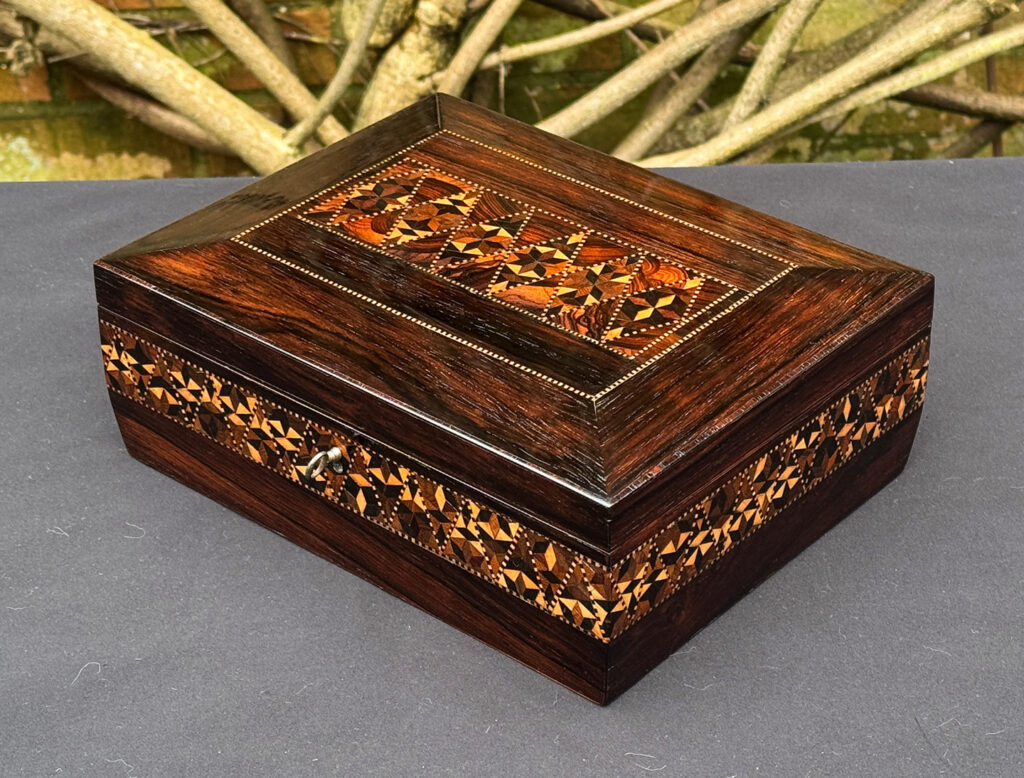 Front right view of a small antique jewellery box in rosewood with parquetry inlay.