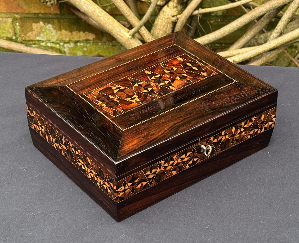 Front left view of a small antique jewellery box in rosewood with parquetry inlay.
