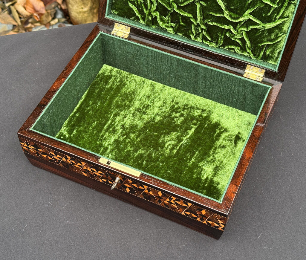 Close interior view of a small antique jewellery box in rosewood with parquetry inlay.