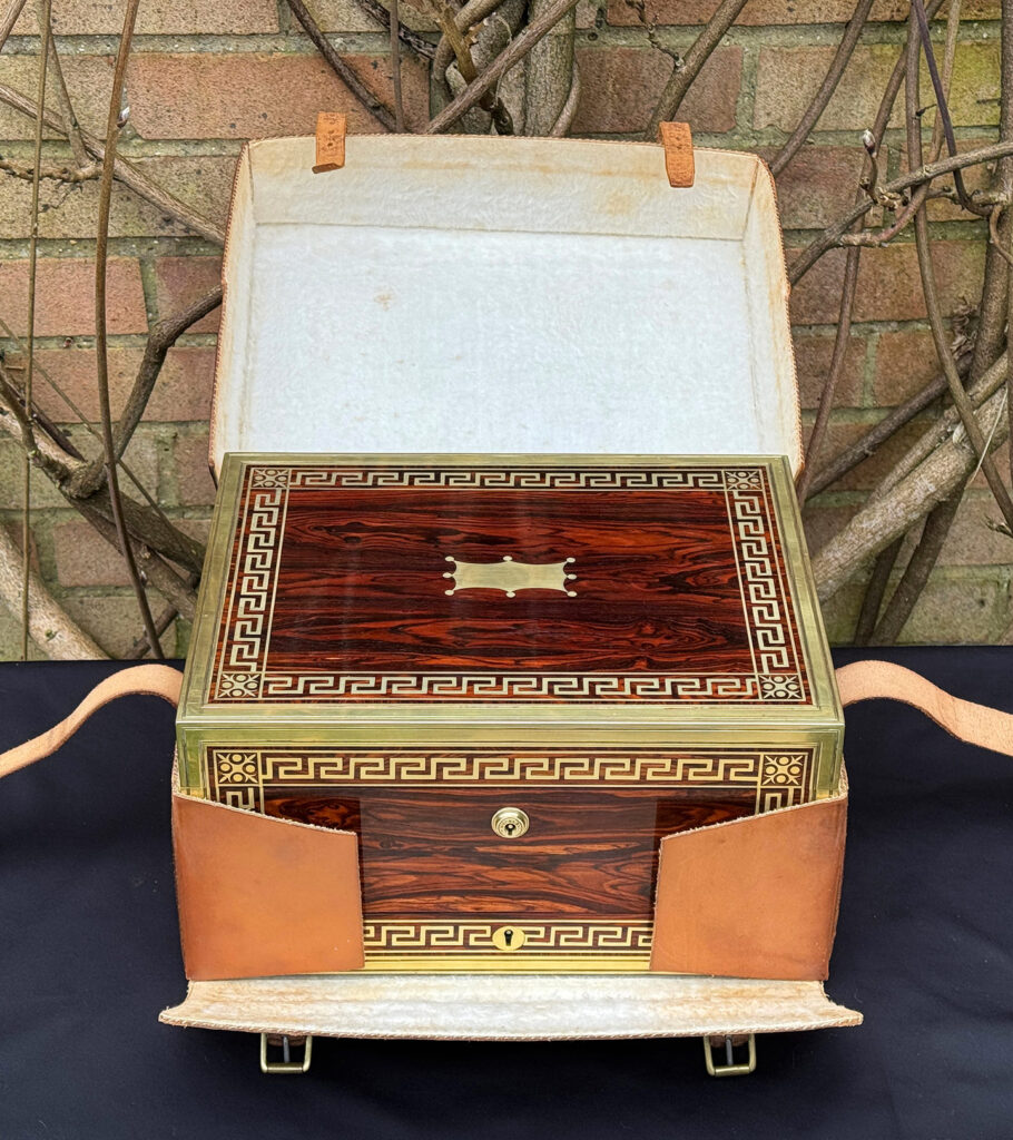 Front view of an antique jewellery box in kingwood, by Wells & Lambe, within its leather outer case.