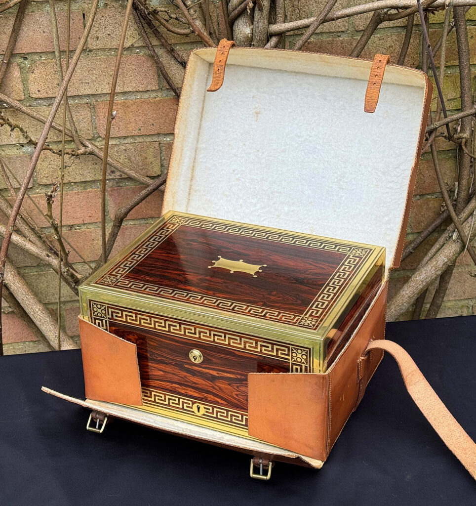 Front right view of an antique jewellery box in kingwood, by Wells & Lambe, within its leather outer case.