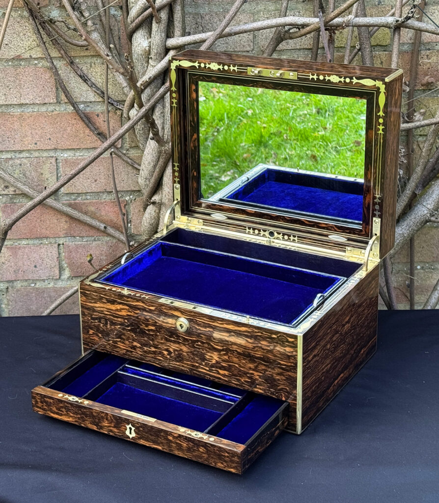 Front right interior view of an antique jewellery box in coromandel by Halstaff & Hannaford, with mirror on display.