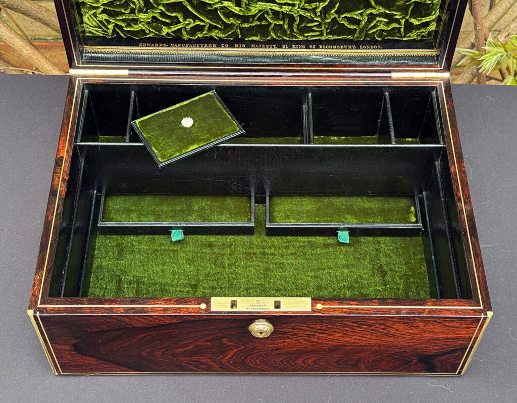 Close interior view of an antique jewellery box in rosewood, by Edwards, with lower concealed drawers opened.