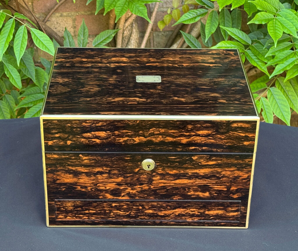 Front view of an antique jewellery box in coromandel with front & side drawer.