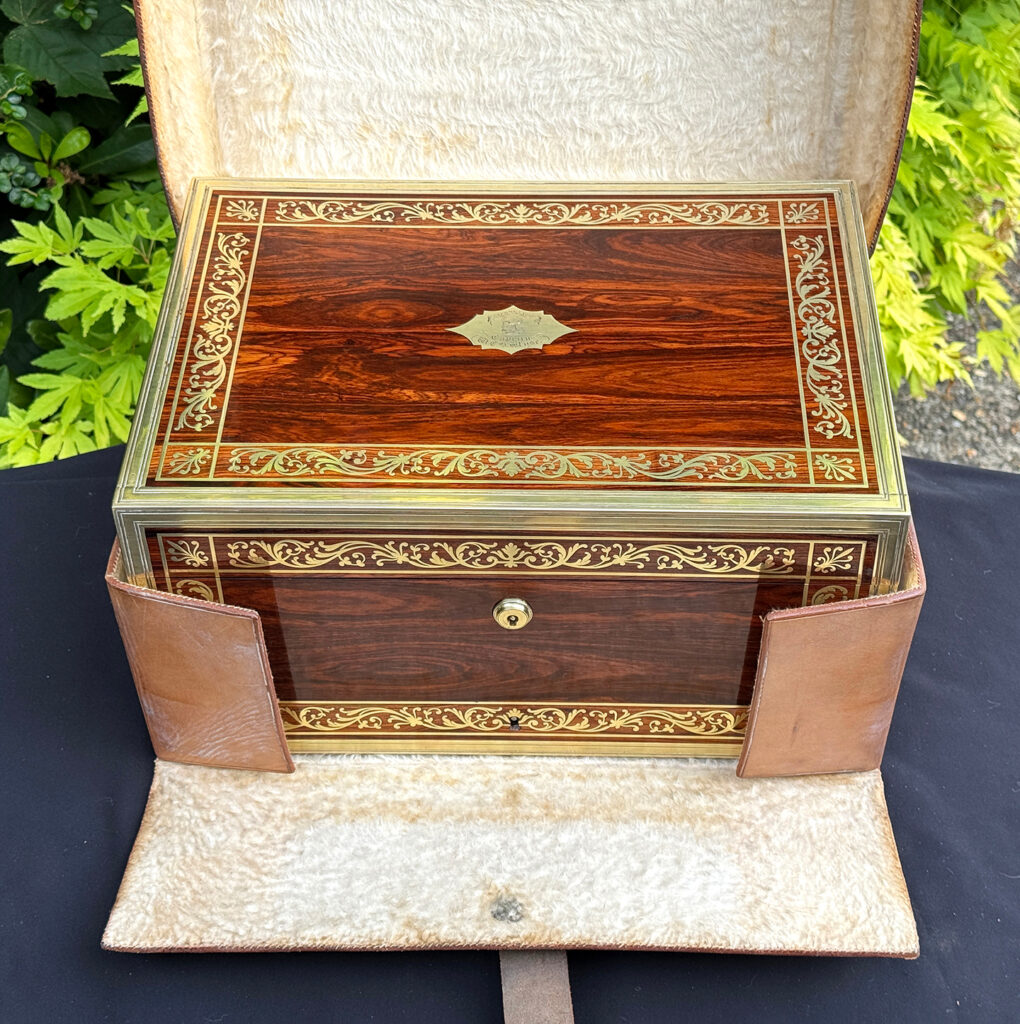 Overhead view of an antique jewellery box in kingwood, by Wells & Lambe, in its outer leather case.