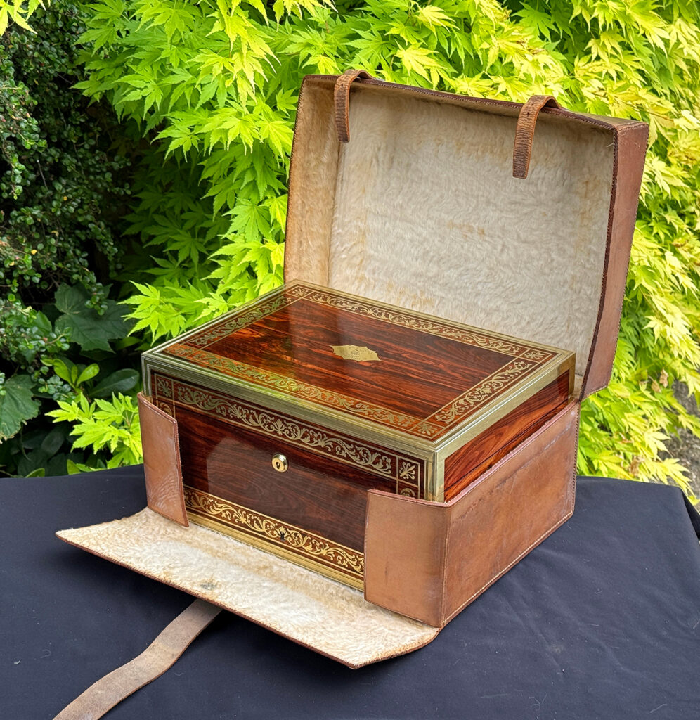Front right view of an antique jewellery box in kingwood, by Wells & Lambe, in its outer leather case.