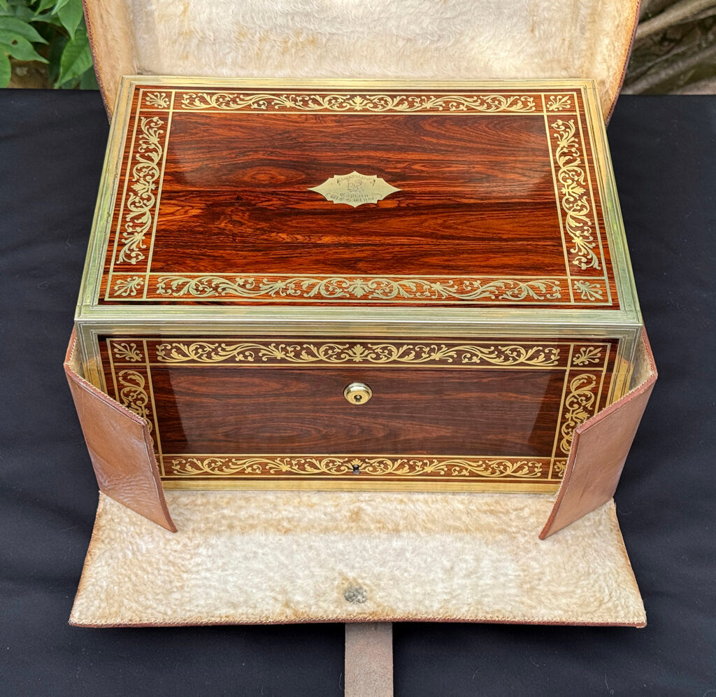 Overhead view of an antique jewellery box in kingwood, by Wells & Lambe, in its outer leather case.